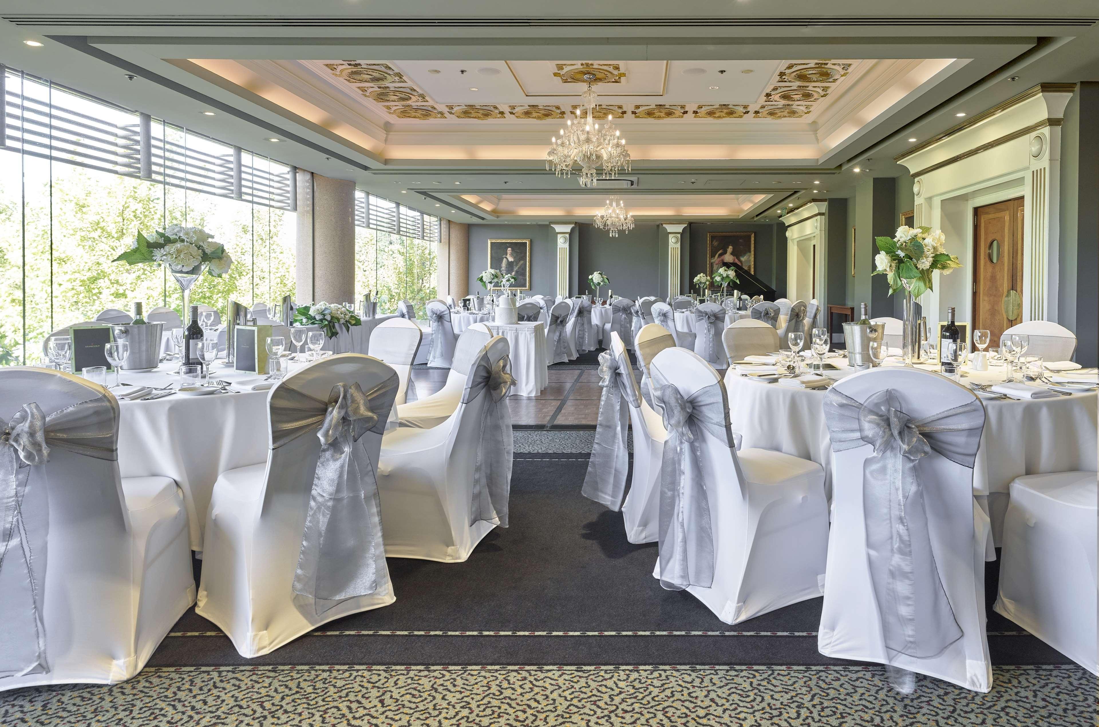 斯坦福德阿德莱德广场酒店 外观 照片 The photo displays an elegantly arranged banquet hall. The room features several round tables covered with white tablecloths, each adorned with silver sashes on the chairs. There are floral centerpieces, possibly white flowers, on the tables, adding 