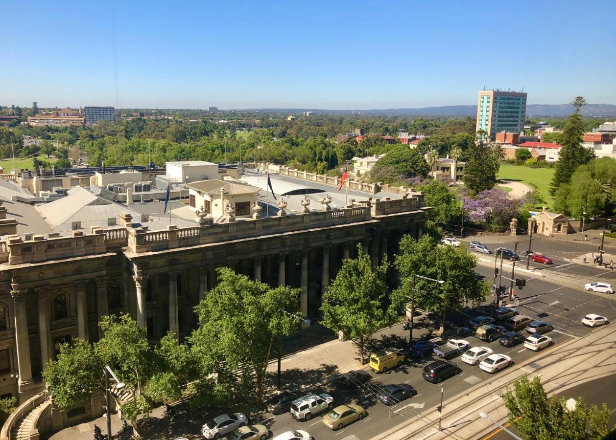 斯坦福德阿德莱德广场酒店 外观 照片 The photo depicts a cityscape view, showcasing a mix of architectural structures and greenery. In the foreground, there is a large, classical building with columns, suggesting it may be a historical or governmental structure. Surrounding the building